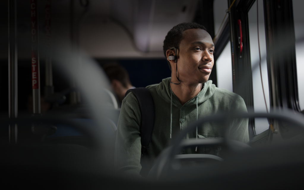 young African American listens to music on his headset so others don't hear but he gets to enjoy while following bus rules