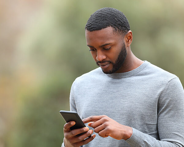 Man using cell phone walking in a park