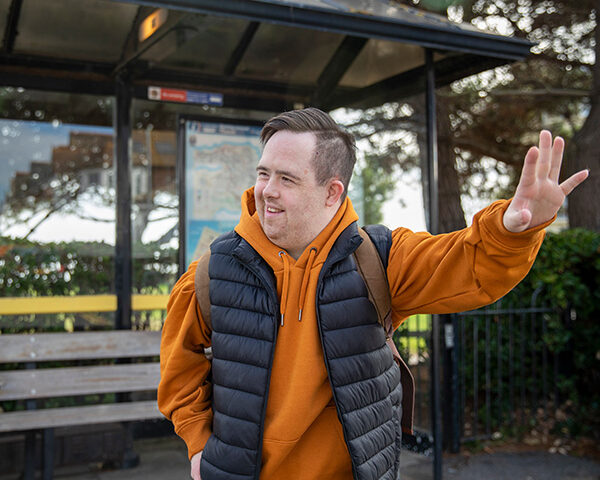 A man hails the bus as it pulls into a station