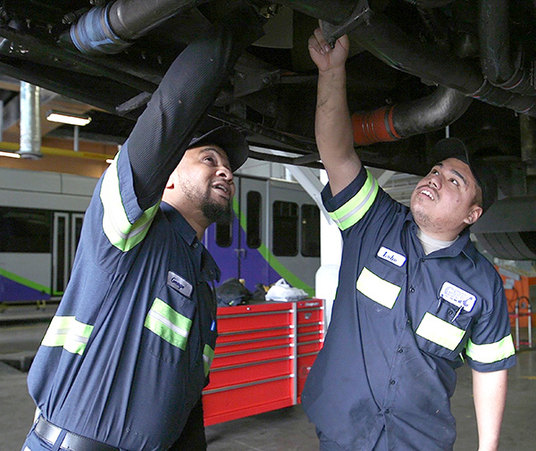 Two mechanics working underneath a raised bus