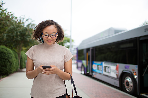 A young woman uses the phone to navigate the bus schedule.