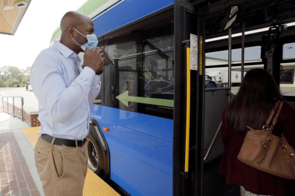 man puts on mask before entering bus for the safety of the community