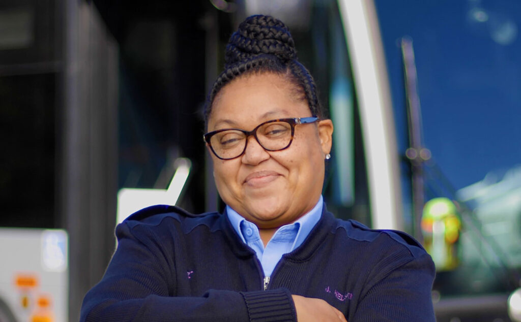 Bus Operator Johnnel stands in front of her vehicle