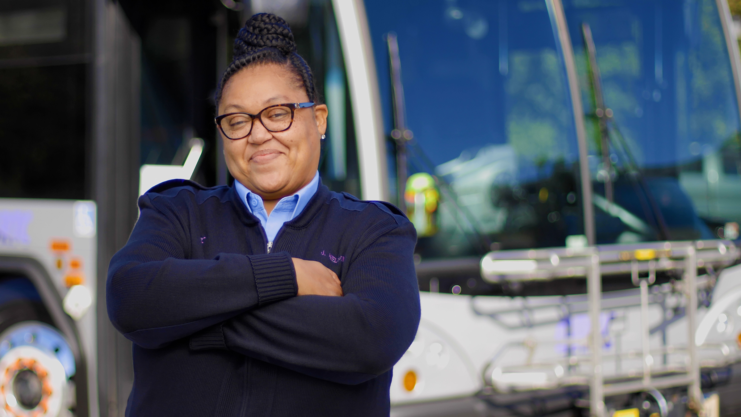 A picture showing a female bus operator in front of a bus