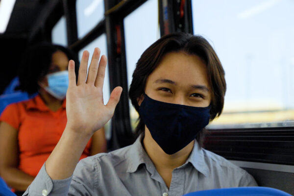 waving masked bus rider