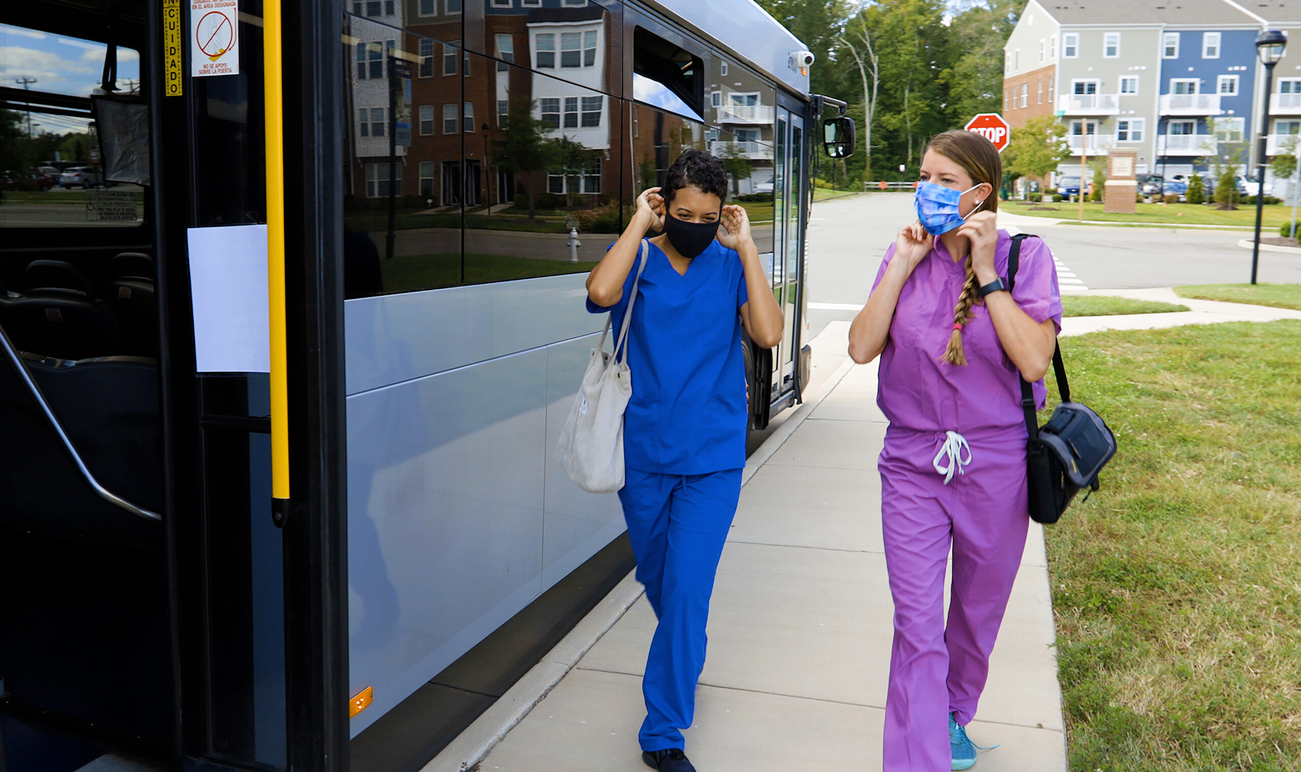 Nurses walking to the back entrance of the bus wearing masks