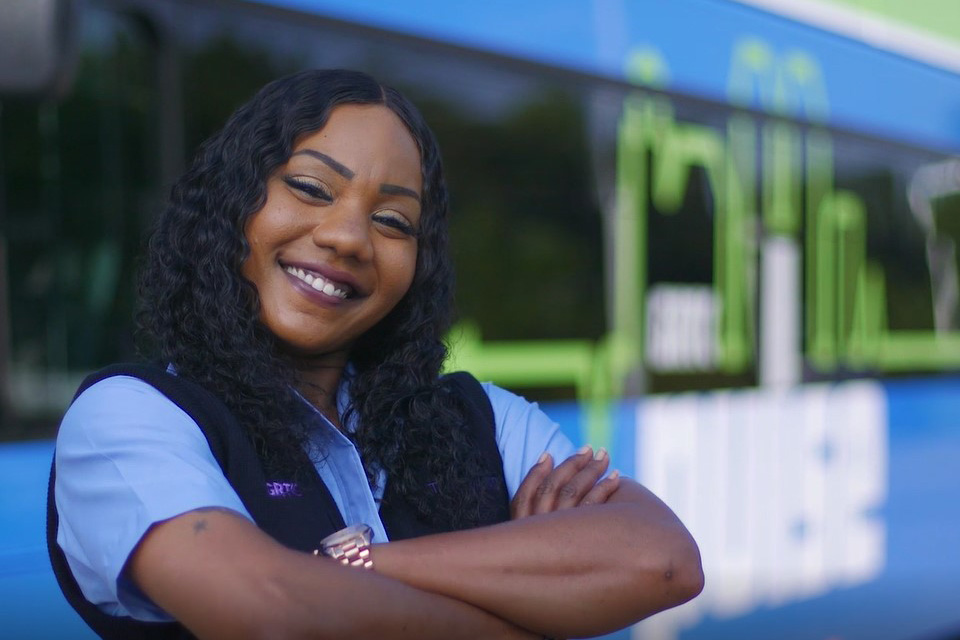 Bus Operator Theresa stands proudly in front of her vehicle