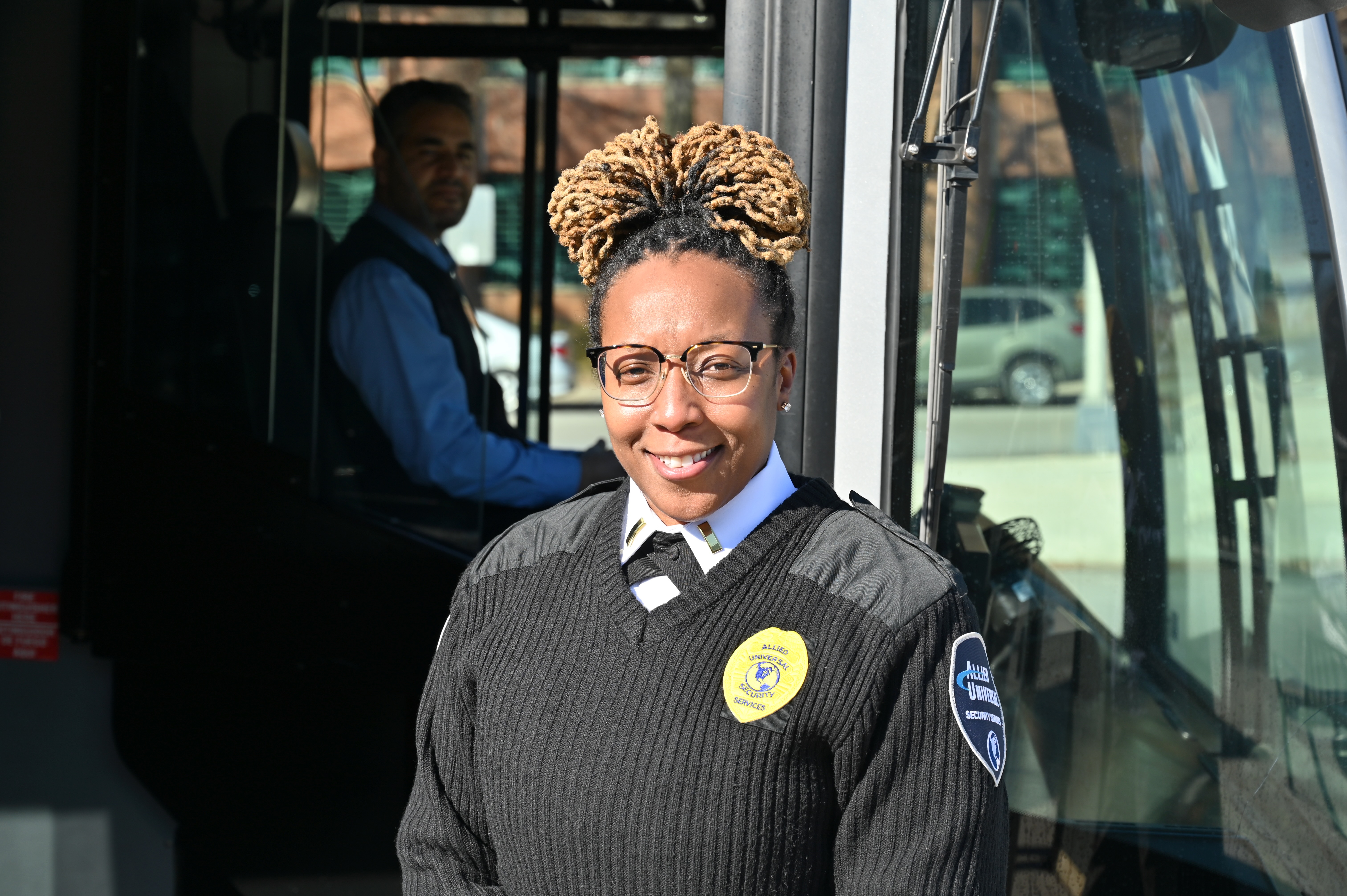 Public Safety Officer standing in a Downtown Transfer Bay, in front of a bus