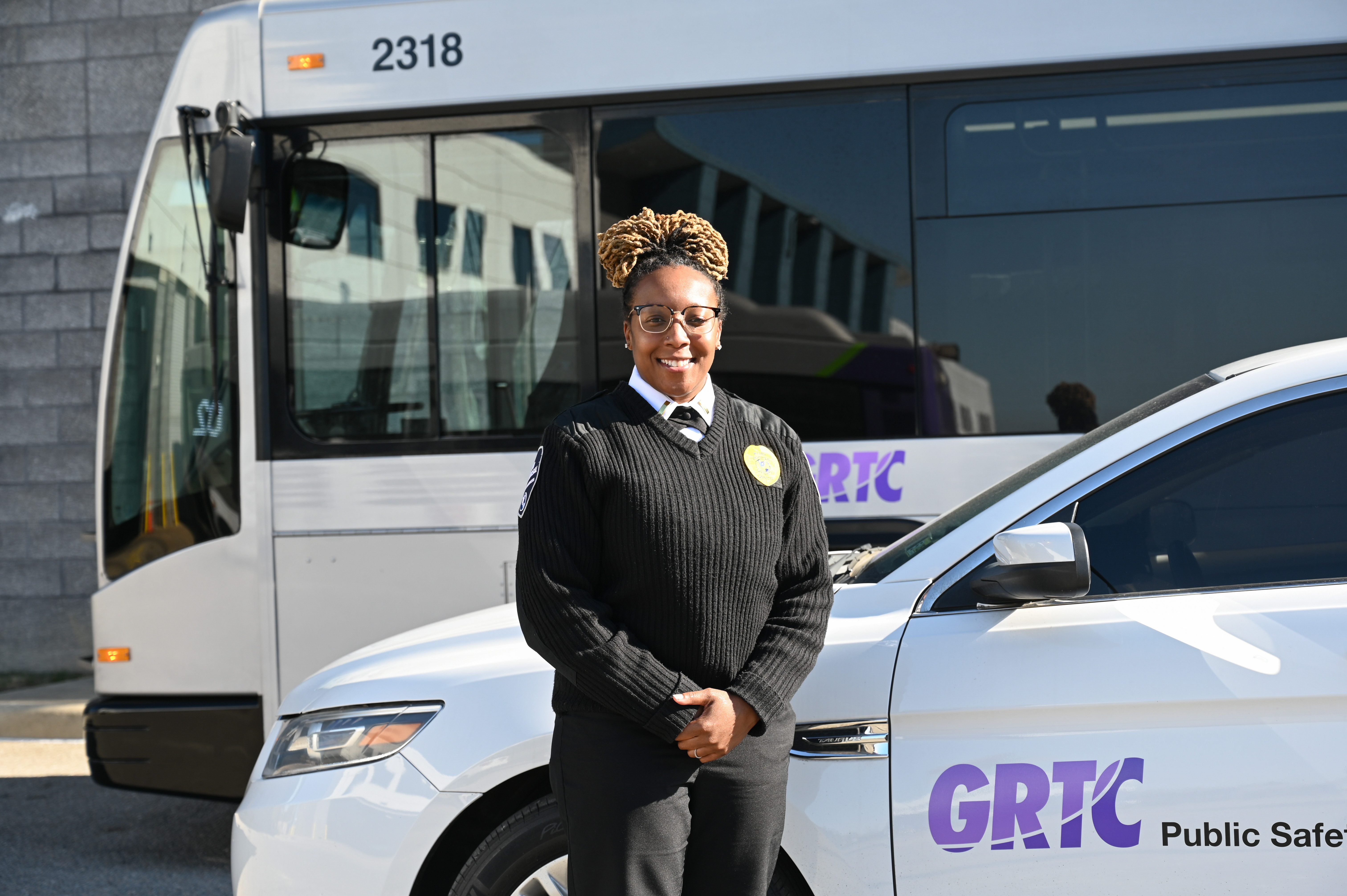 Public Safety Officer stands before the Public Safety Vehicle, with a bus in the background