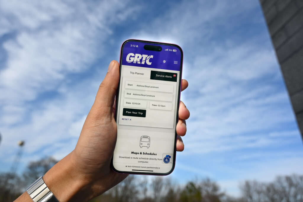 A phone held up to show the mobile version of the new GRTC homepage